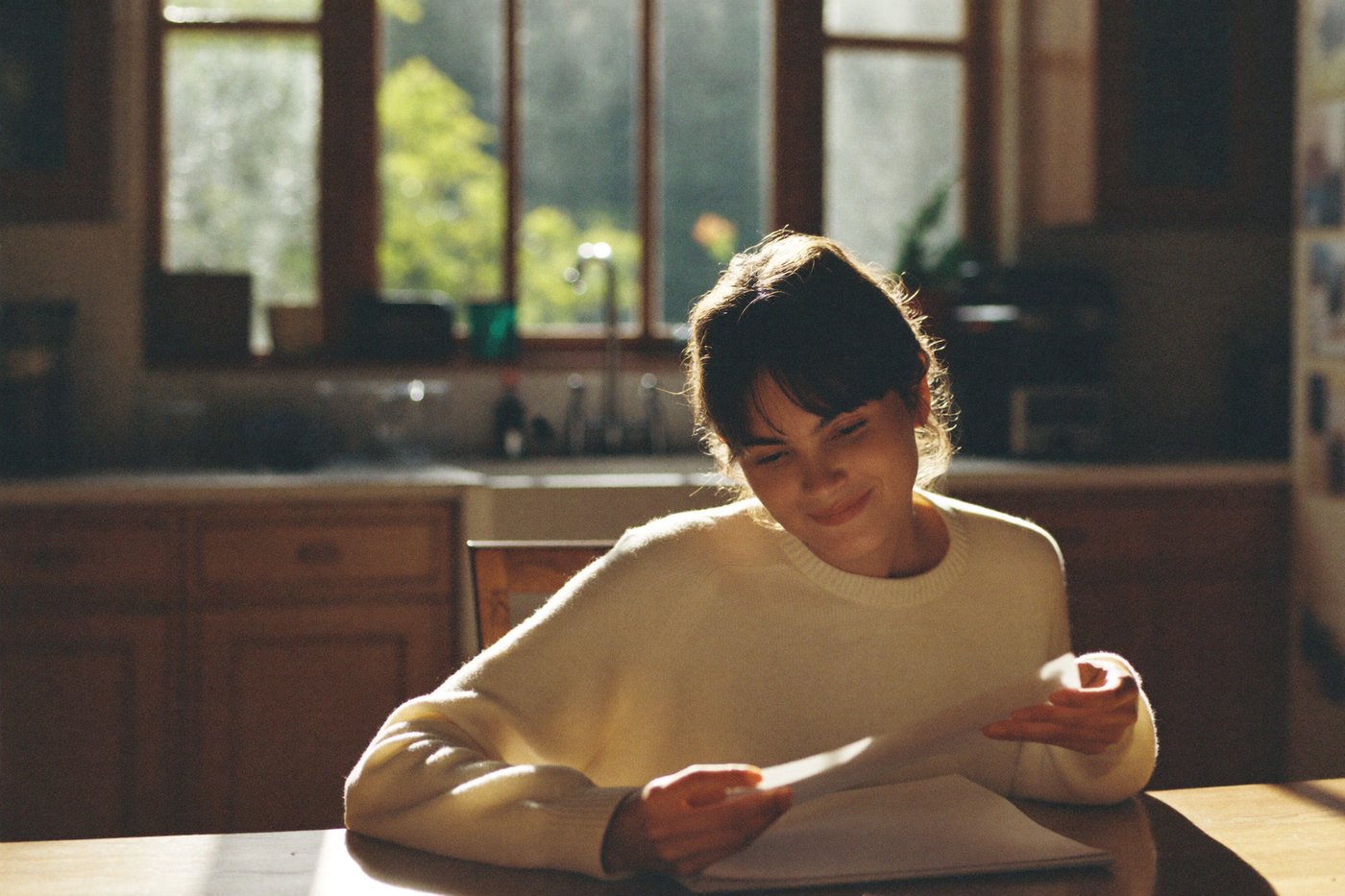 A woman reading her purpose report at a sunlit kitchen table